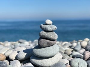 Stack of balanced pebbles on a beach with a serene ocean backdrop, exuding calmness and tranquility.